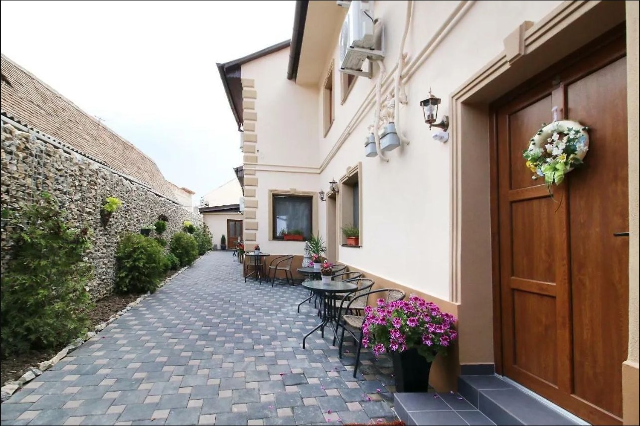Curtea interioară pavată, cu ziduri de piatră, plante și mobilier exterior
