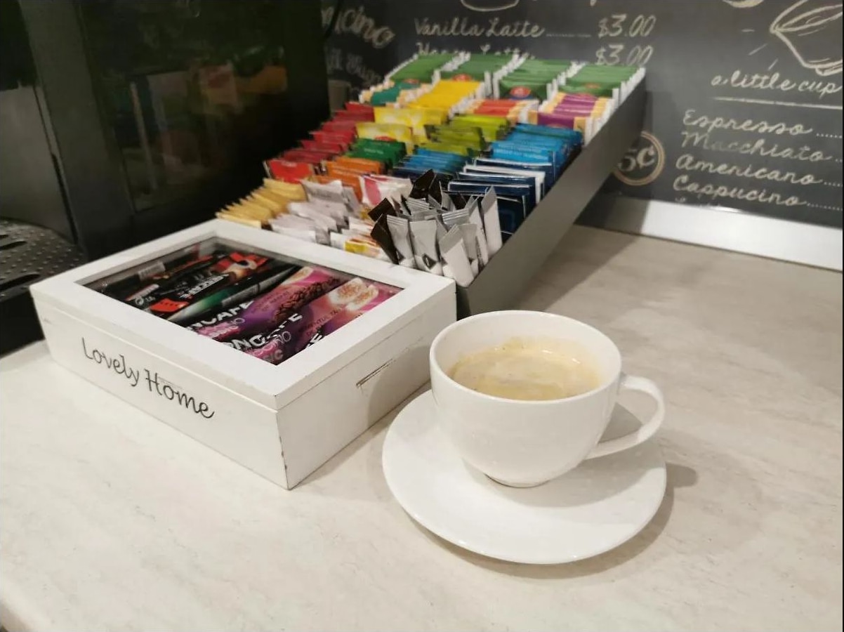 Ceașcă de cafea și cutie cu plicuri de ceai și cafea