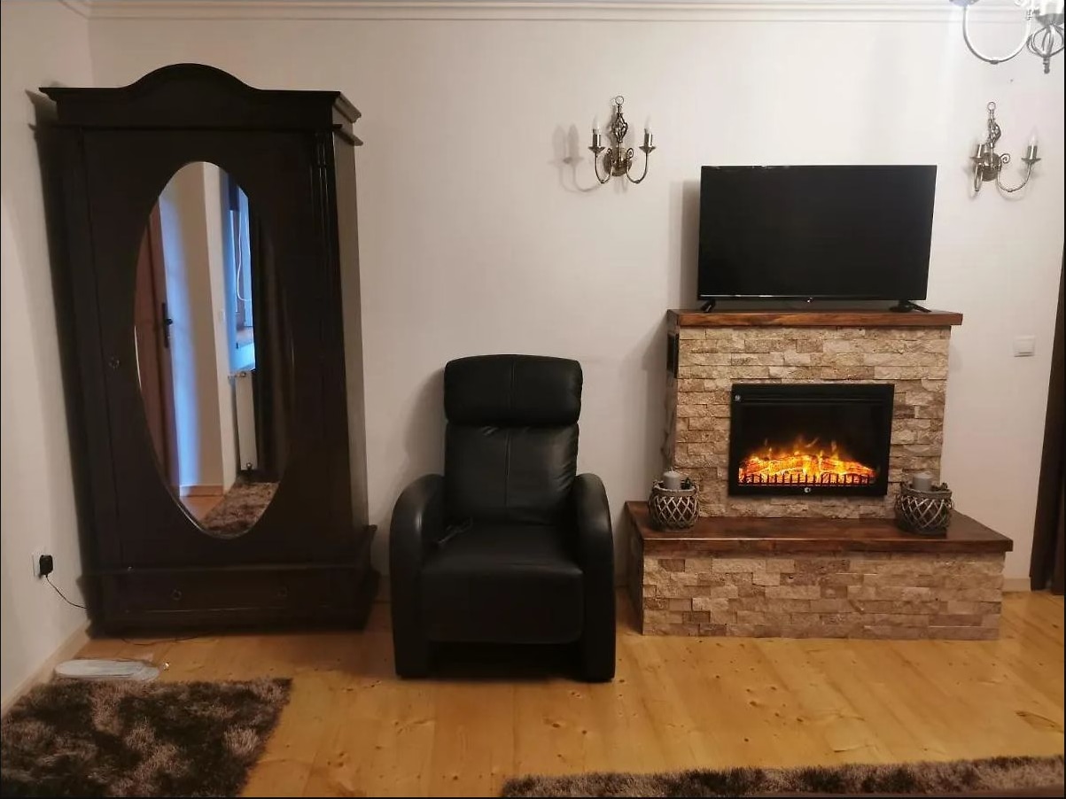 Șemineu decorativ din piatră, fotoliu de piele și șifonier din lemn