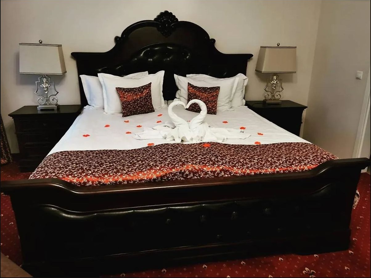 Pat cu tăblie sculptată din lemn închis și lenjerie cu model floral