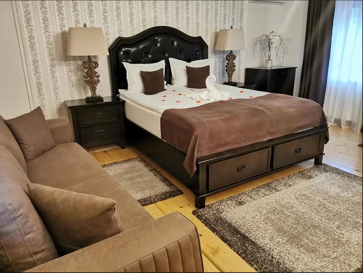 Cameră cu canapea, pat din lemn închis și covor deschis